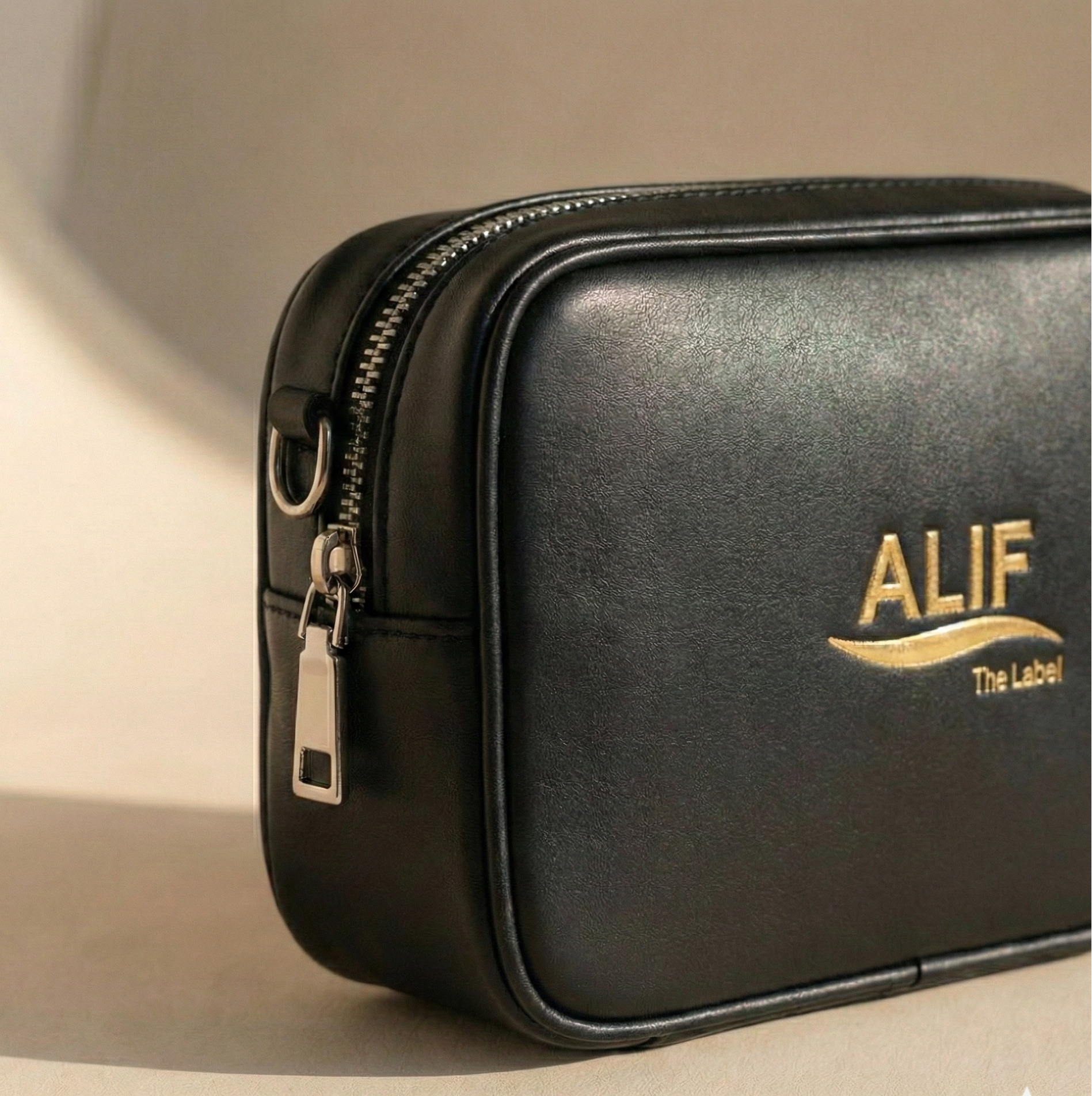 Black leather pouch with 'ALIF The Label' logo on a beige background