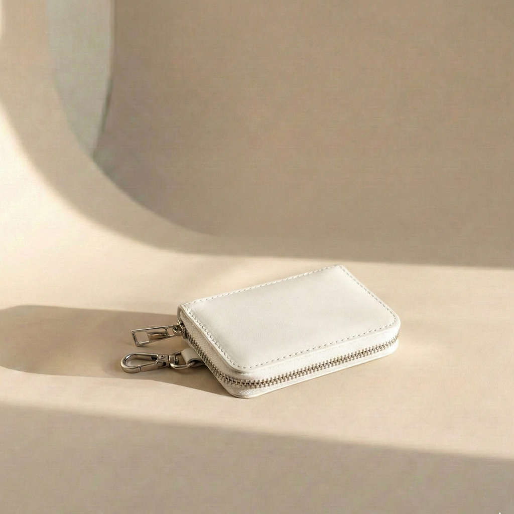 White wallet with a zipper on a beige surface